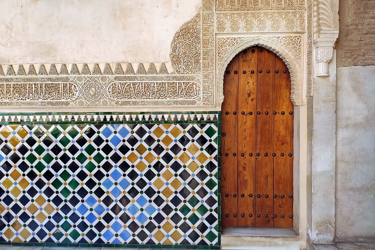 A tiled dado and a carved wooden door in the Alhambra