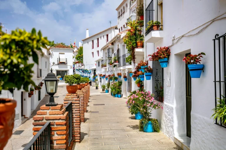 A whitewashed street lined with blue flowerpots in Mijas
